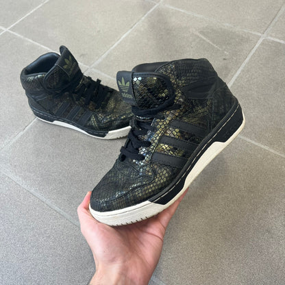 Adidas 2016 M Attitude Revive Snakeskin Sneakers are dark green sneakers covered in a shiny snakeskin-textured material, featuring black side stripes and a dark green Adidas Trefoil logo on the tongue. The sole is white with black accents.