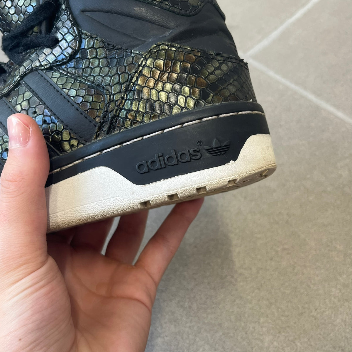 Adidas 2016 M Attitude Revive Snakeskin Sneakers are dark green sneakers covered in a shiny snakeskin-textured material, featuring black side stripes and a dark green Adidas Trefoil logo on the tongue. The sole is white with black accents.