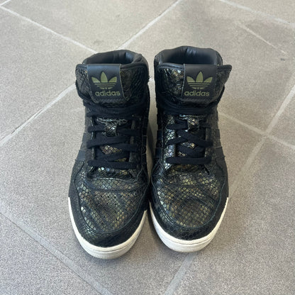 Adidas 2016 M Attitude Revive Snakeskin Sneakers are dark green sneakers covered in a shiny snakeskin-textured material, featuring black side stripes and a dark green Adidas Trefoil logo on the tongue. The sole is white with black accents.