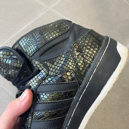 Adidas 2016 M Attitude Revive Snakeskin Sneakers are dark green sneakers covered in a shiny snakeskin-textured material, featuring black side stripes and a dark green Adidas Trefoil logo on the tongue. The sole is white with black accents.