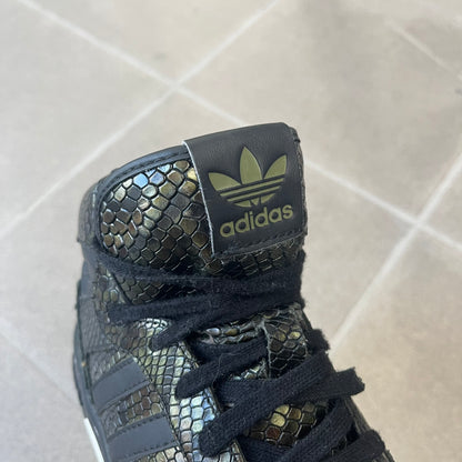 Adidas 2016 M Attitude Revive Snakeskin Sneakers are dark green sneakers covered in a shiny snakeskin-textured material, featuring black side stripes and a dark green Adidas Trefoil logo on the tongue. The sole is white with black accents.