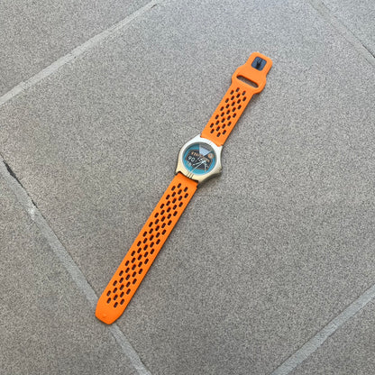 Adidas 90s Streetball 2 Analog Watch features a silver-tone metal case with a blue dial. The face includes an Adidas logo, orange “Streetball 2” branding, and white “90:78” graphics. It is equipped with a Japan movement and water-resistant construction. The watch is finished with orange rubber straps, which are a replacement/non-original strap design.
