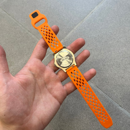Adidas 90s Streetball 2 Analog Watch features a silver-tone metal case with a blue dial. The face includes an Adidas logo, orange “Streetball 2” branding, and white “90:78” graphics. It is equipped with a Japan movement and water-resistant construction. The watch is finished with orange rubber straps, which are a replacement/non-original strap design.
