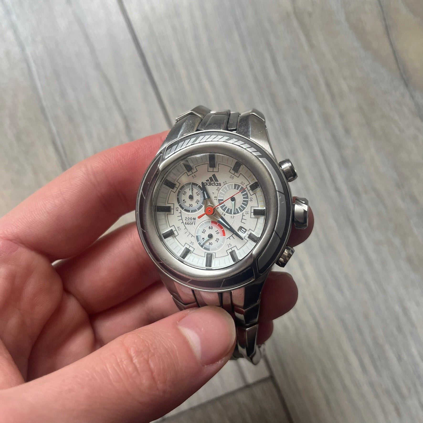 Adidas Adi-Star Pro Chrono ADP-1017 Analog Watch is a stainless steel timepiece with a white dial featuring the Adidas logo and three subdials for chronograph functions. It has two side buttons and a crown for adjustments, with a detailed and textured dial design. The watch is water resistant up to 200 meters.