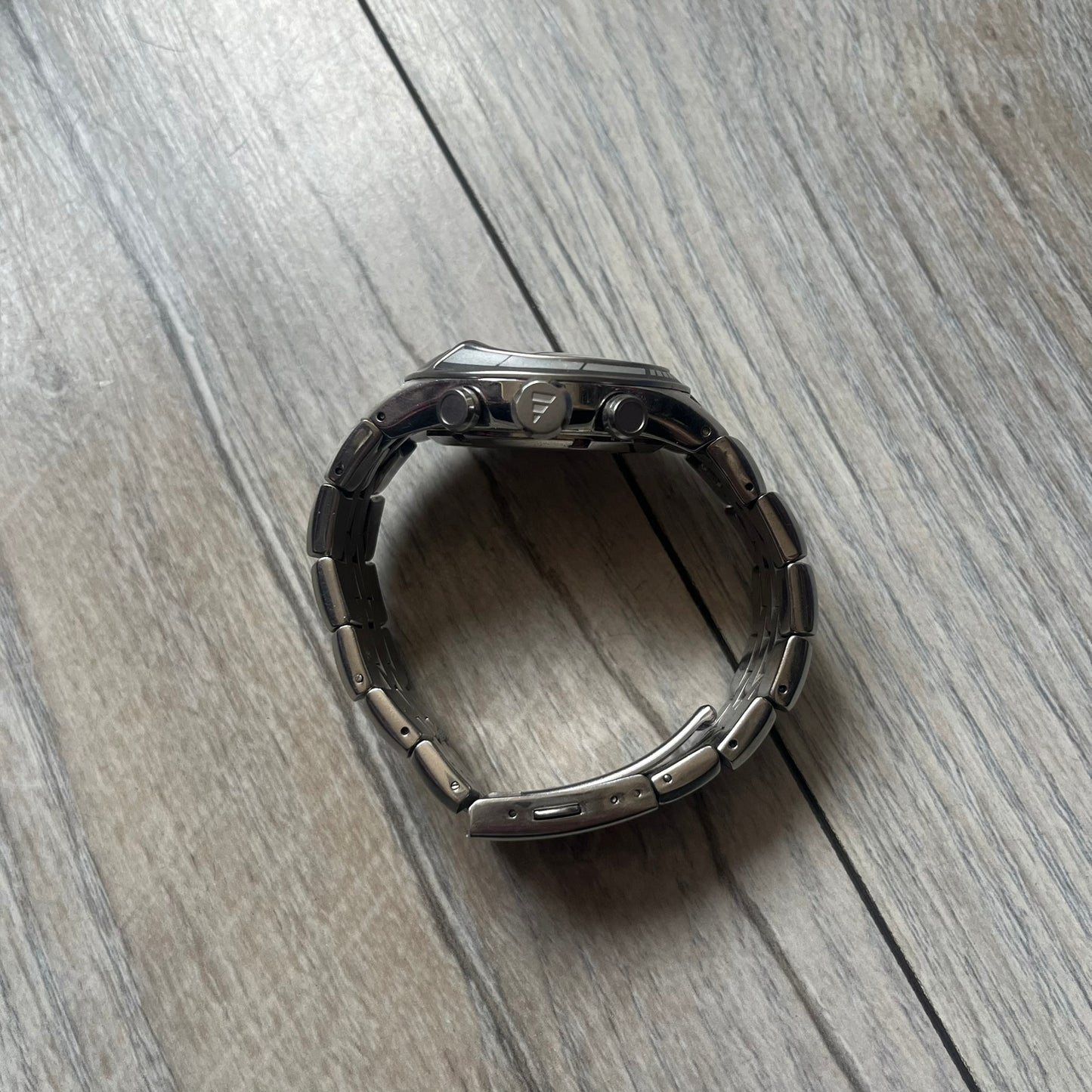 Adidas Adi-Star Pro Chrono ADP-1017 Analog Watch is a stainless steel timepiece with a white dial featuring the Adidas logo and three subdials for chronograph functions. It has two side buttons and a crown for adjustments, with a detailed and textured dial design. The watch is water resistant up to 200 meters.