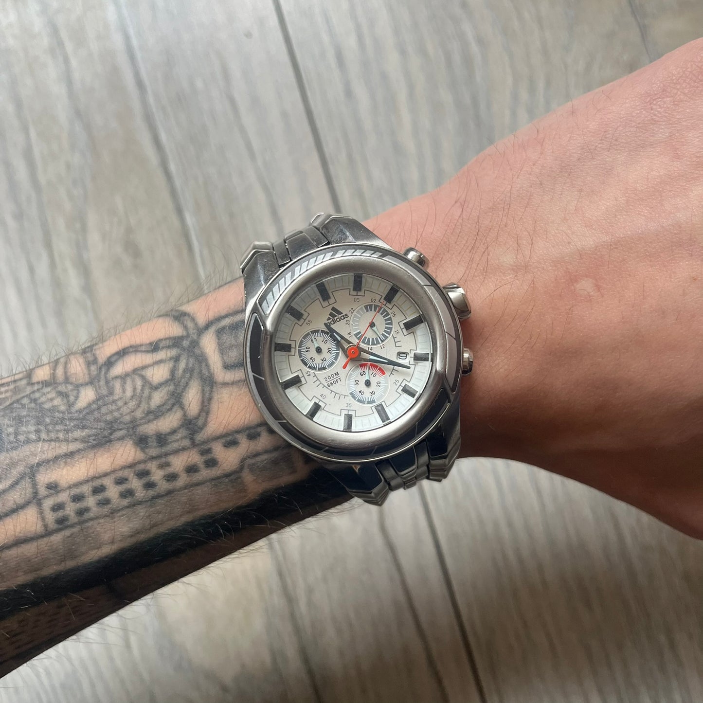 Adidas Adi-Star Pro Chrono ADP-1017 Analog Watch is a stainless steel timepiece with a white dial featuring the Adidas logo and three subdials for chronograph functions. It has two side buttons and a crown for adjustments, with a detailed and textured dial design. The watch is water resistant up to 200 meters.