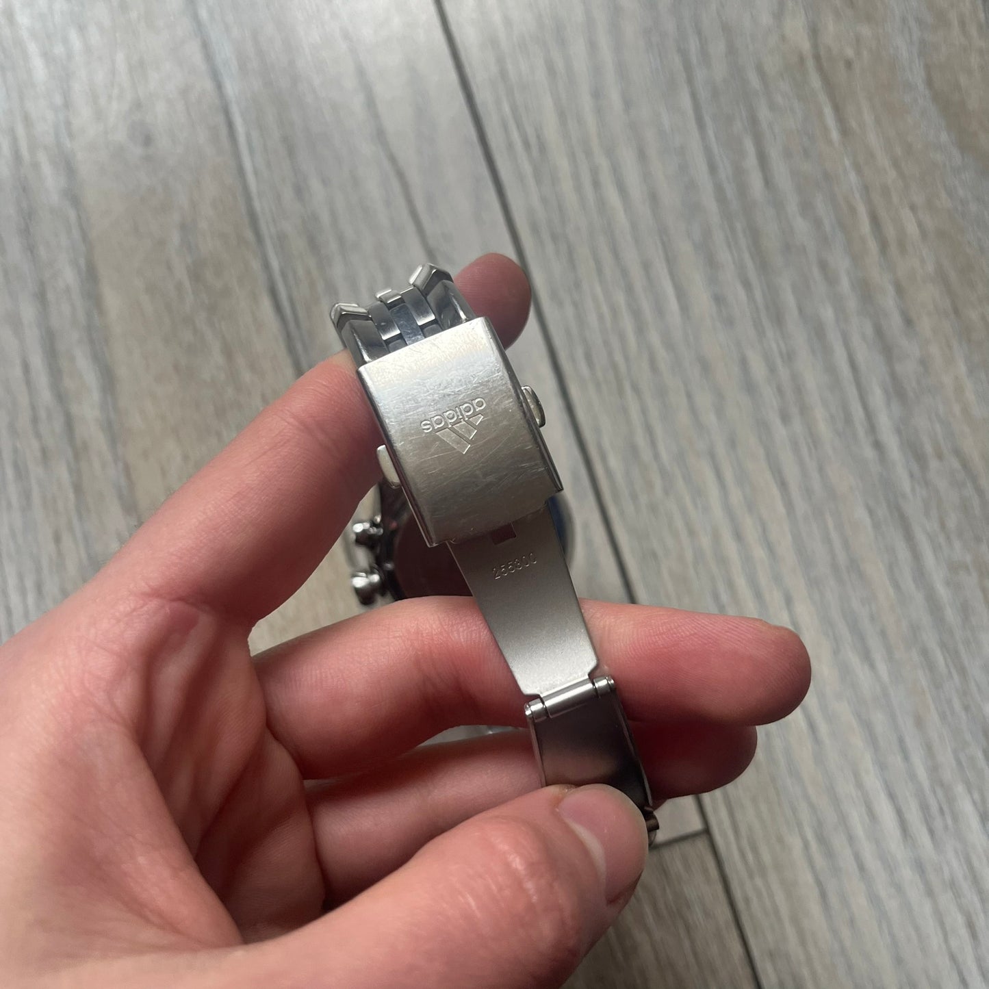 Adidas Adi-Star Pro Chrono ADP-1017 Analog Watch is a stainless steel timepiece with a white dial featuring the Adidas logo and three subdials for chronograph functions. It has two side buttons and a crown for adjustments, with a detailed and textured dial design. The watch is water resistant up to 200 meters.