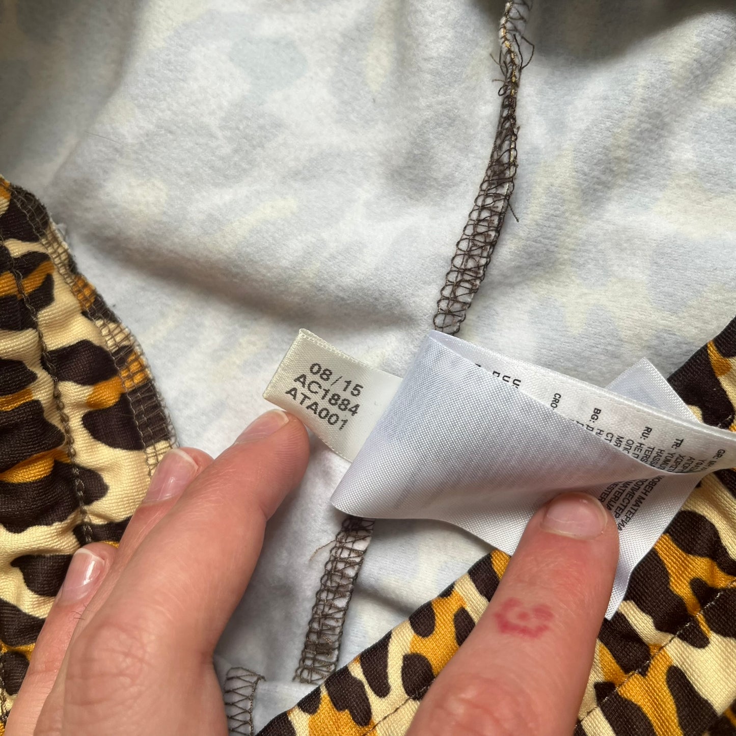 Adidas x Jeremy Scott 2015 Leopard Print Track Pants feature an all-over orange, brown, and white leopard print pattern throughout the garment. The design includes brown Adidas three-stripe detailing down both sides, zippered pockets, brown drawstrings, and an embroidered Adidas Trefoil logo. This pair was released as part of the Adidas Originals by Jeremy Scott collaboration.