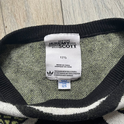 Adidas Jeremy Scott Alien Face 2012 Sweater features an all-over print of white alien faces arranged in alternating upright and upside-down patterns. The eyes of each alien are replaced with green Adidas Originals logos, creating a distinctive graphic design.