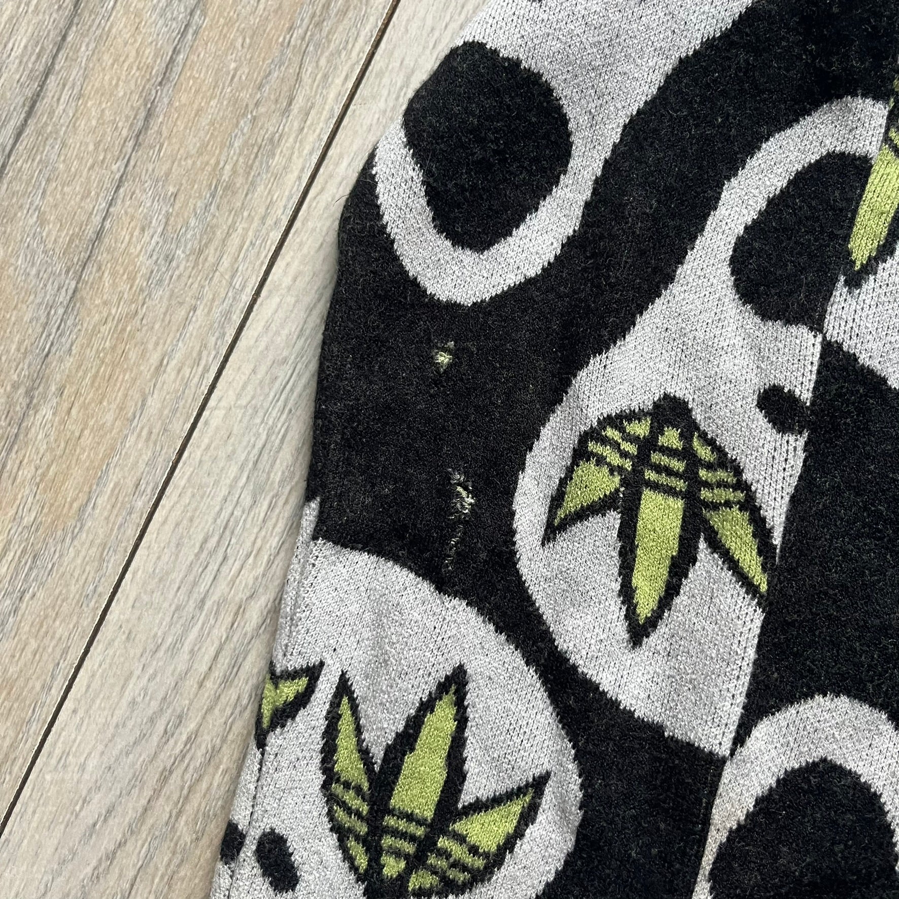 Adidas Jeremy Scott Alien Face 2012 Sweater features an all-over print of white alien faces arranged in alternating upright and upside-down patterns. The eyes of each alien are replaced with green Adidas Originals logos, creating a distinctive graphic design.