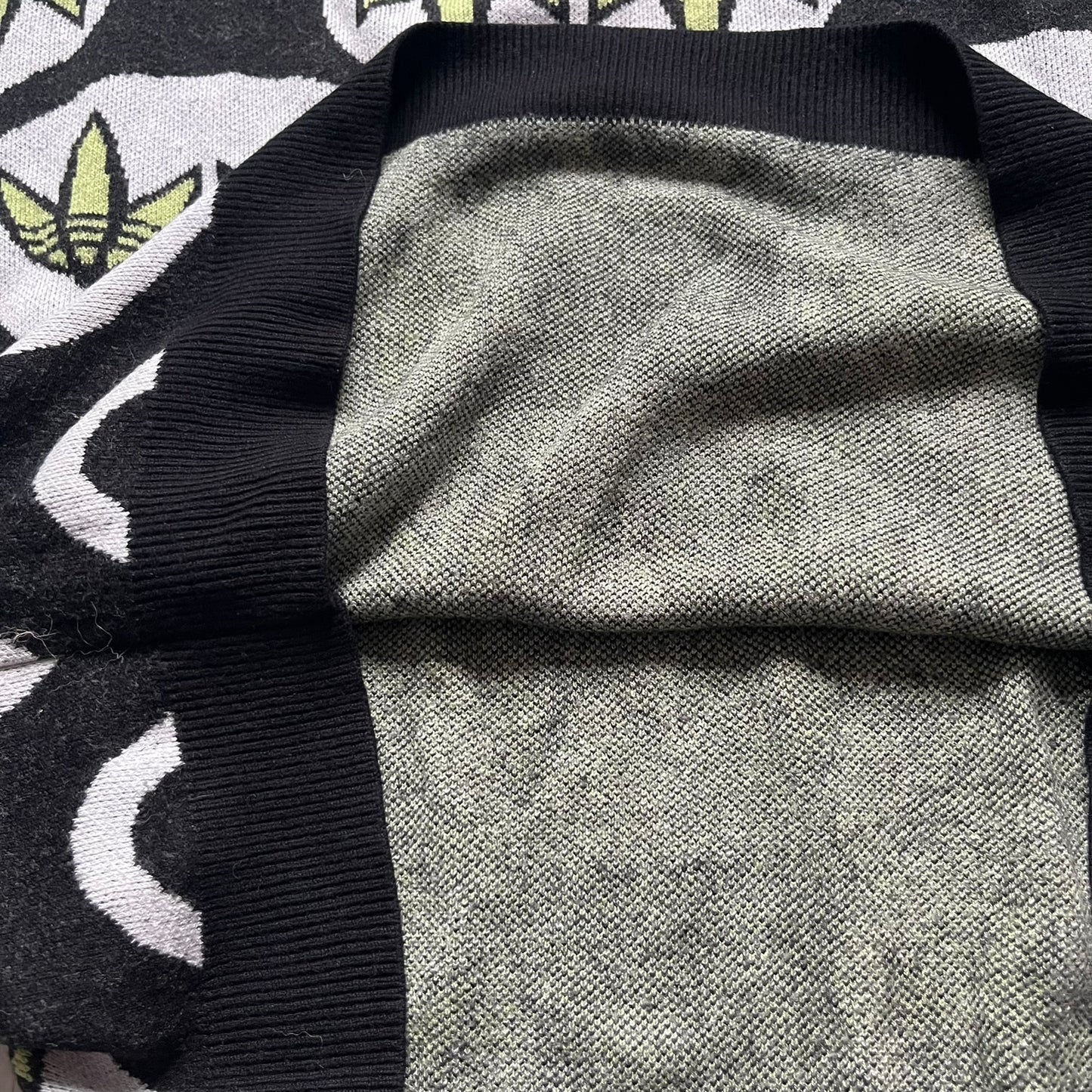 Adidas Jeremy Scott Alien Face 2012 Sweater features an all-over print of white alien faces arranged in alternating upright and upside-down patterns. The eyes of each alien are replaced with green Adidas Originals logos, creating a distinctive graphic design.