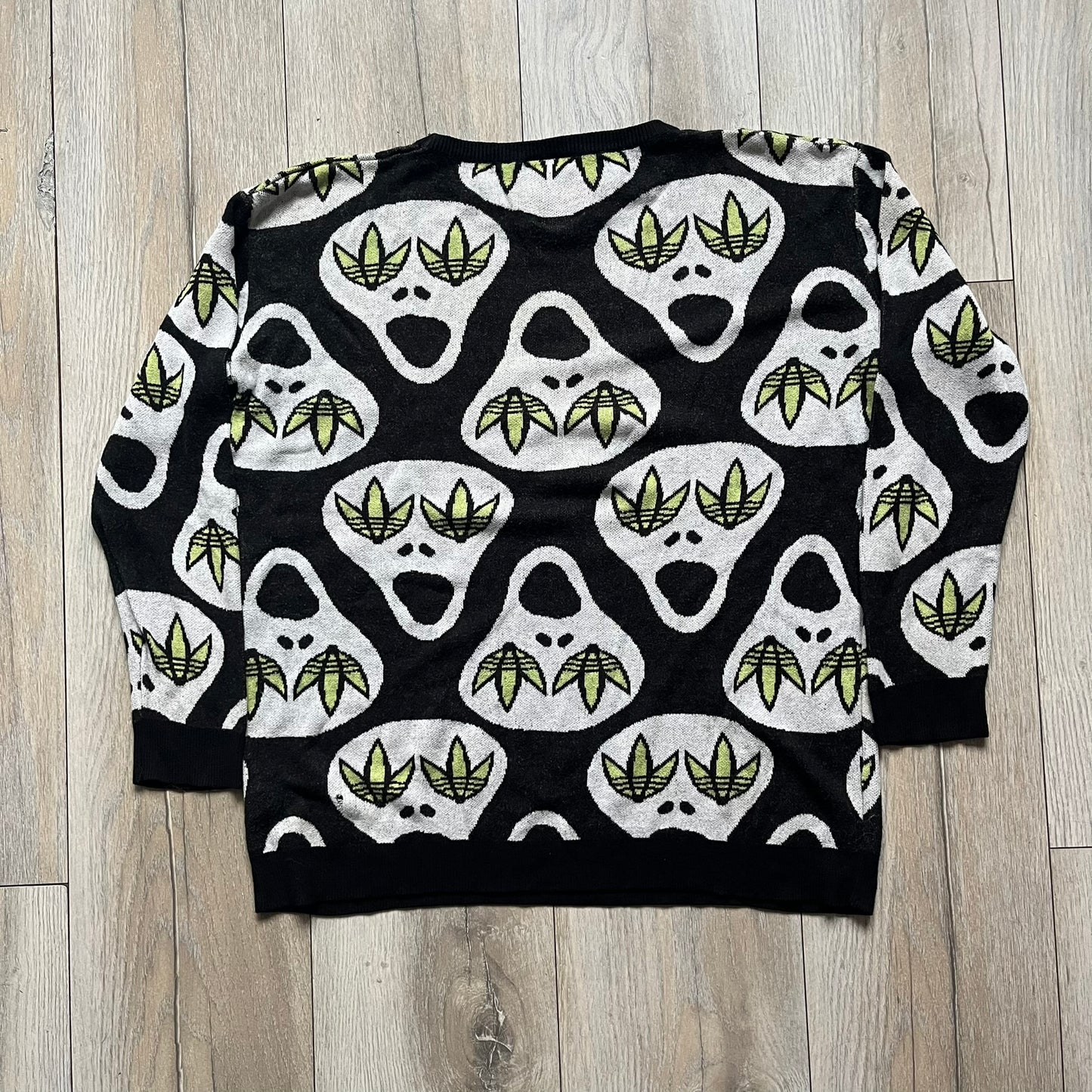 Adidas Jeremy Scott Alien Face 2012 Sweater features an all-over print of white alien faces arranged in alternating upright and upside-down patterns. The eyes of each alien are replaced with green Adidas Originals logos, creating a distinctive graphic design.