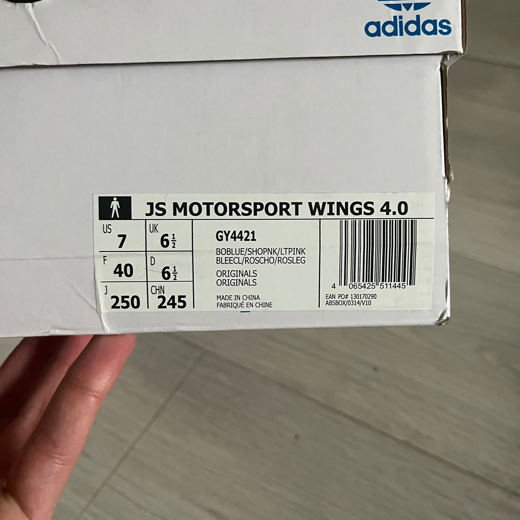 The Adidas Jeremy Scott Motorsport Wings 4.0 features a leather upper in blue with a gradient transitioning to green, accented by shock pink and light pink logo stripes. This high-top sneaker includes breathable perforations, a grippy rubber outsole, padded tongue, and signature Wings detailing at the collar. Released in 2022, the limited edition model comes with its original box and is crafted for comfort and style.