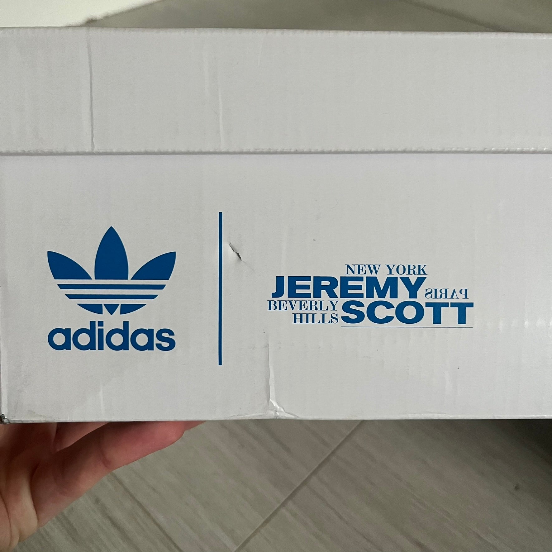 The Adidas Jeremy Scott Motorsport Wings 4.0 features a leather upper in blue with a gradient transitioning to green, accented by shock pink and light pink logo stripes. This high-top sneaker includes breathable perforations, a grippy rubber outsole, padded tongue, and signature Wings detailing at the collar. Released in 2022, the limited edition model comes with its original box and is crafted for comfort and style.
