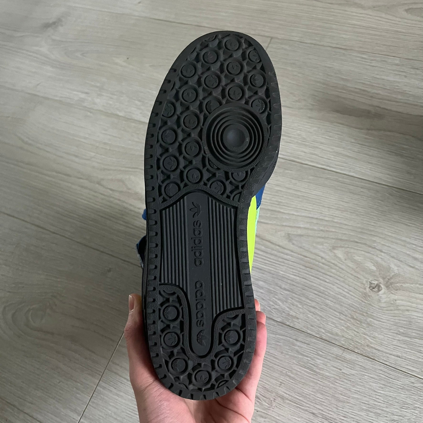 The Adidas Jeremy Scott Motorsport Wings 4.0 features a leather upper in blue with a gradient transitioning to green, accented by shock pink and light pink logo stripes. This high-top sneaker includes breathable perforations, a grippy rubber outsole, padded tongue, and signature Wings detailing at the collar. Released in 2022, the limited edition model comes with its original box and is crafted for comfort and style.