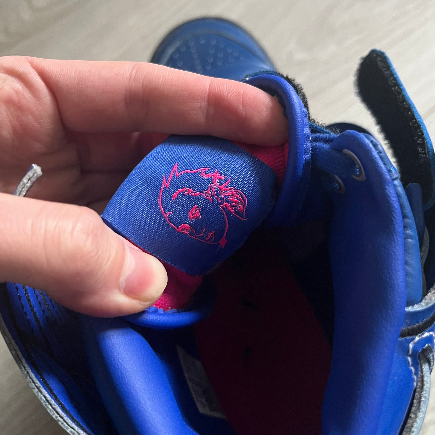 The Adidas Jeremy Scott Motorsport Wings 4.0 features a leather upper in blue with a gradient transitioning to green, accented by shock pink and light pink logo stripes. This high-top sneaker includes breathable perforations, a grippy rubber outsole, padded tongue, and signature Wings detailing at the collar. Released in 2022, the limited edition model comes with its original box and is crafted for comfort and style.