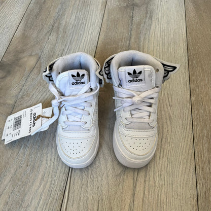 Adidas x Jeremy Scott Wings 4.0 Kids Sneakers were released on May 5, 2022. They feature white premium leather uppers with black Three Stripes, black heel tabs, and Jeremy Scott Wings branding. The high-top design includes a padded collar and tongue, along with a rubber herringbone outsole. One shoe is bigger than the other, making it primarily suitable as a display or collectible item.
