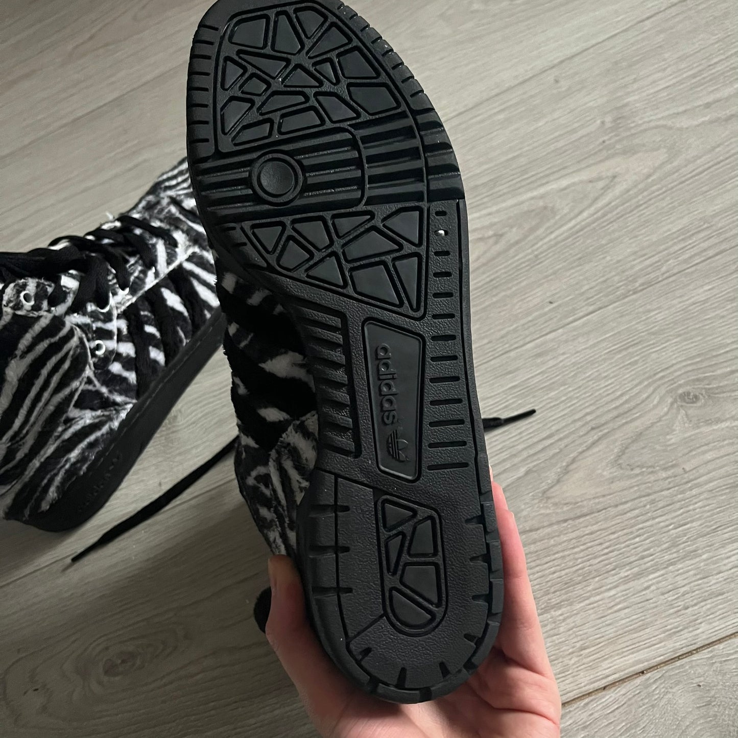 Adidas Jeremy Scott Zebra Black &amp; White Sneakers – Sample pair, Style G95749. High-top sneakers featuring black and white faux-fur zebra print, a 3D tail at the heel, rubber soles, and front lace closure. From the FW13 Jeremy Scott for Adidas collection, these iconic sneakers combine classic adidas design with signature crazy JS styling.&nbsp;
