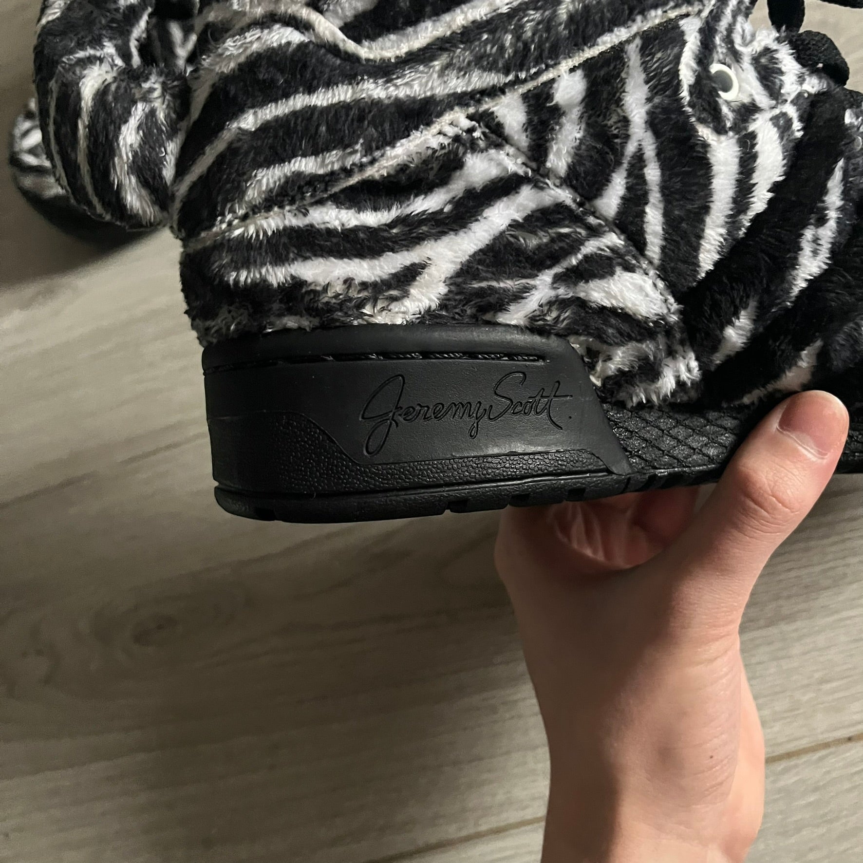 Adidas Jeremy Scott Zebra Black &amp; White Sneakers – Sample pair, Style G95749. High-top sneakers featuring black and white faux-fur zebra print, a 3D tail at the heel, rubber soles, and front lace closure. From the FW13 Jeremy Scott for Adidas collection, these iconic sneakers combine classic adidas design with signature crazy JS styling.&nbsp;