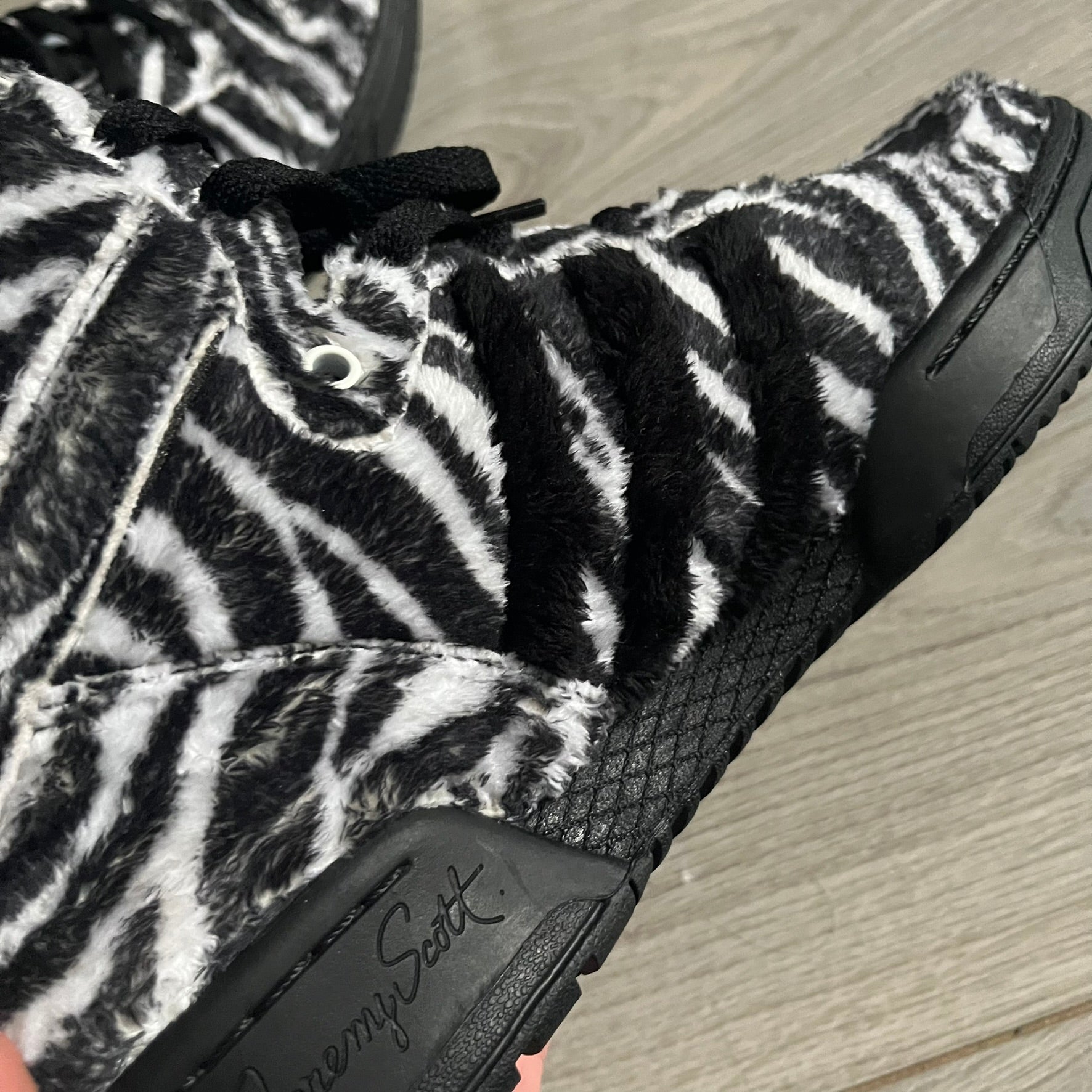 Adidas Jeremy Scott Zebra Black &amp; White Sneakers – Sample pair, Style G95749. High-top sneakers featuring black and white faux-fur zebra print, a 3D tail at the heel, rubber soles, and front lace closure. From the FW13 Jeremy Scott for Adidas collection, these iconic sneakers combine classic adidas design with signature crazy JS styling.&nbsp;