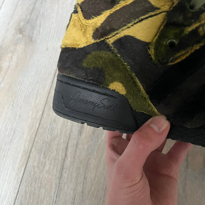 Adidas Jeremy Scott “Camo Bear” Sneakers (Style Q20917) released on March 16, 2013, in Earth Green/Black/Shioli. Featuring plush fleece uppers with a camouflage pattern, black three stripes, and a fully stuffed teddy bear head and arms on the tongue. Includes Jeremy Scott signature detailing on the inside heel and a black rubber sole.