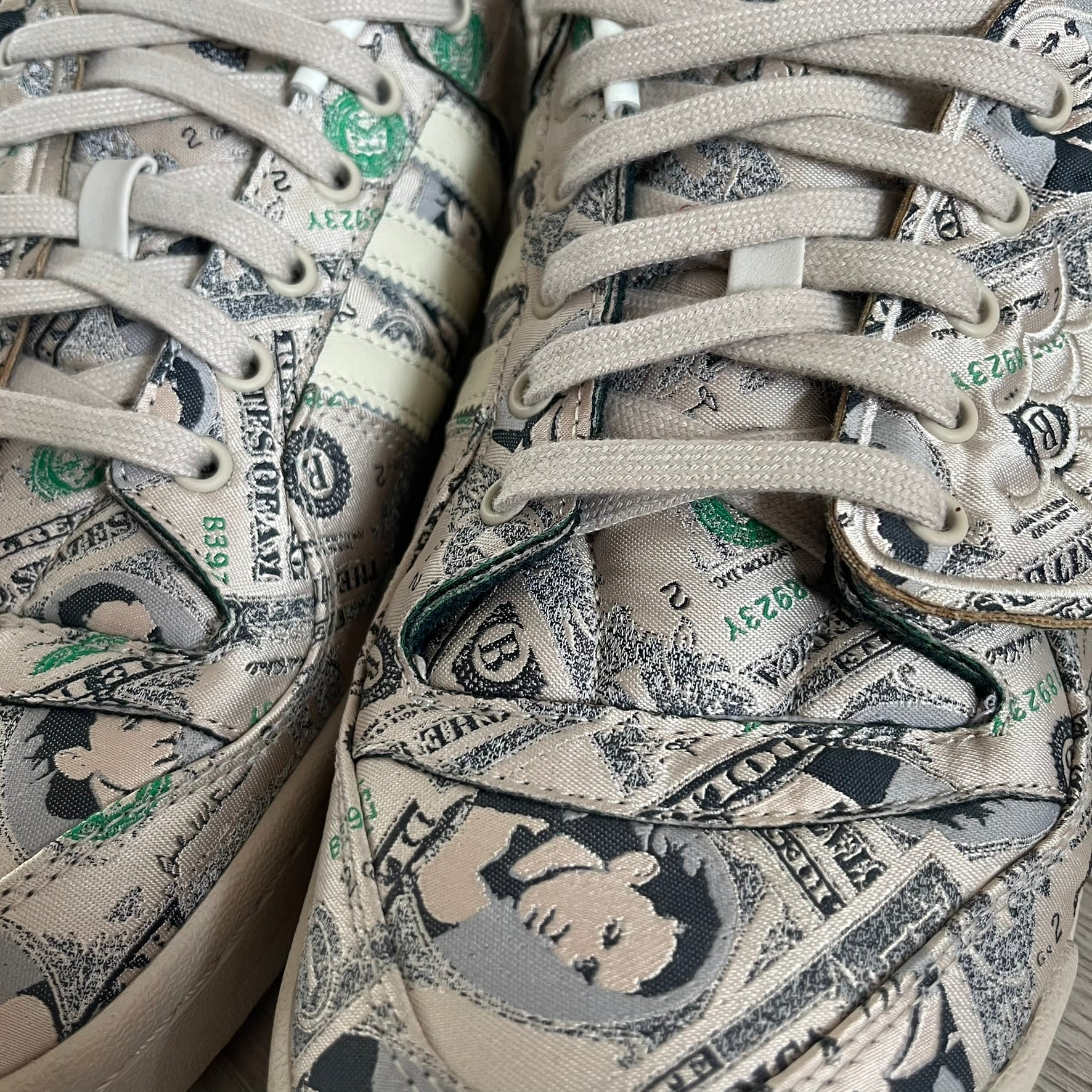 Adidas Jeremy Scott x Forum Wings 1.0 Low Money, style GX6393, in a Bliss/Off White/Bliss colorway. This pair features a textile upper covered in Jeremy Scott’s signature currency-themed graphic, swapping George Washington’s portrait for his own. The iconic 3D wings sit on the side of the shoe, with embossed adidas branding and Scott’s signature on opposite panels. Built with an EVA wedge for lightweight cushioning and a durable rubber cup sole. First released on October 21, 2021.