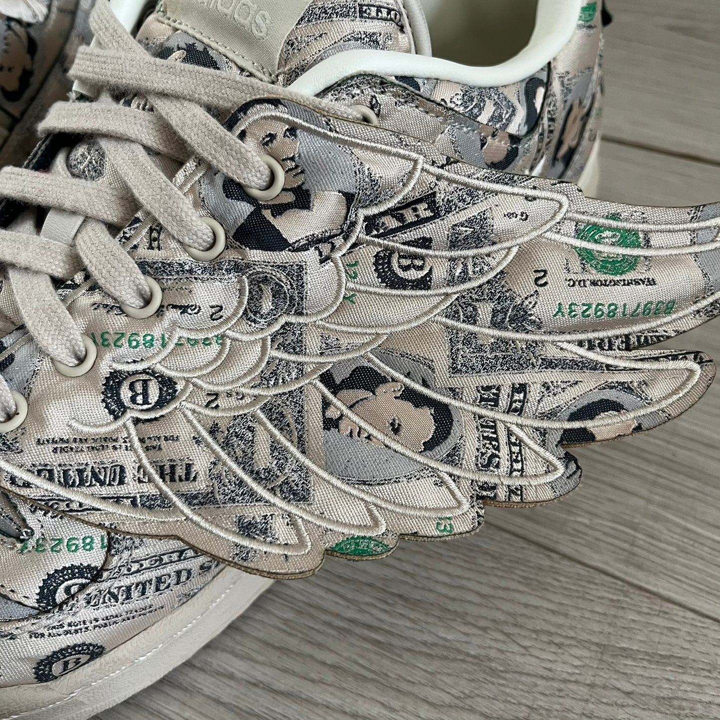 Adidas Jeremy Scott x Forum Wings 1.0 Low Money, style GX6393, in a Bliss/Off White/Bliss colorway. This pair features a textile upper covered in Jeremy Scott’s signature currency-themed graphic, swapping George Washington’s portrait for his own. The iconic 3D wings sit on the side of the shoe, with embossed adidas branding and Scott’s signature on opposite panels. Built with an EVA wedge for lightweight cushioning and a durable rubber cup sole. First released on October 21, 2021.