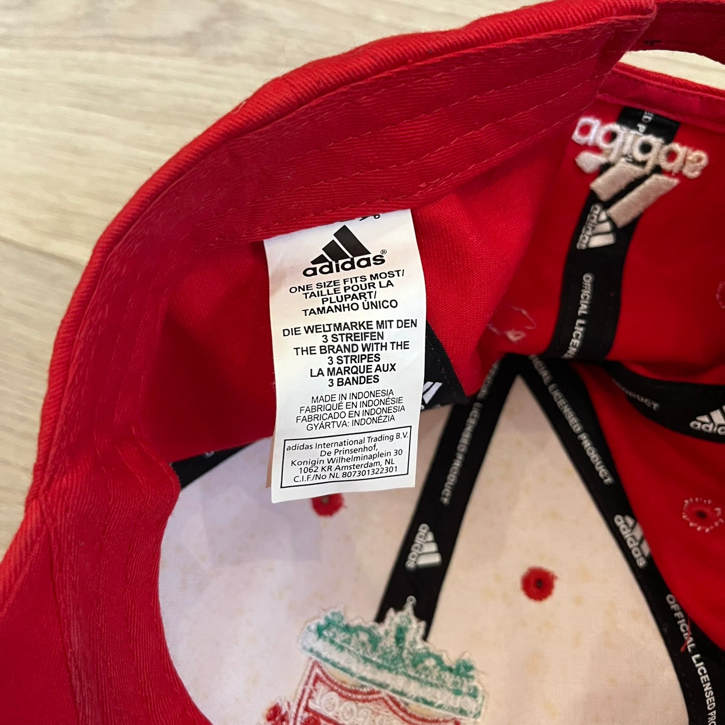 Adidas Liverpool 2007/08 Football Cap is a red cap featuring three white embroidered stripes across the front and an embroidered Liverpool crest at the center. The back is finished with a white embroidered Adidas logo and an adjustable metal clasp engraved with Liverpool detailing. Produced for the 2007/08 season