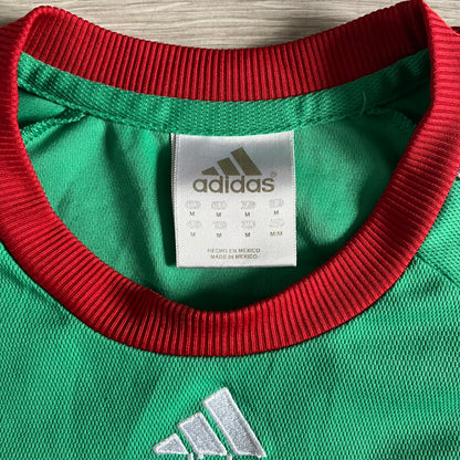 Adidas 2007-08 Mexico Powerade Limited Edition 3/4 Tee in green with red collar and white Adidas sleeve stripes. Features embroidered Adidas logo beneath the neck, Mexico crest on the heart, and a “Powerade Edición Especial” patch at the lower front. Extremely rare, issued only to select Coca-Cola store owners in Mexico.