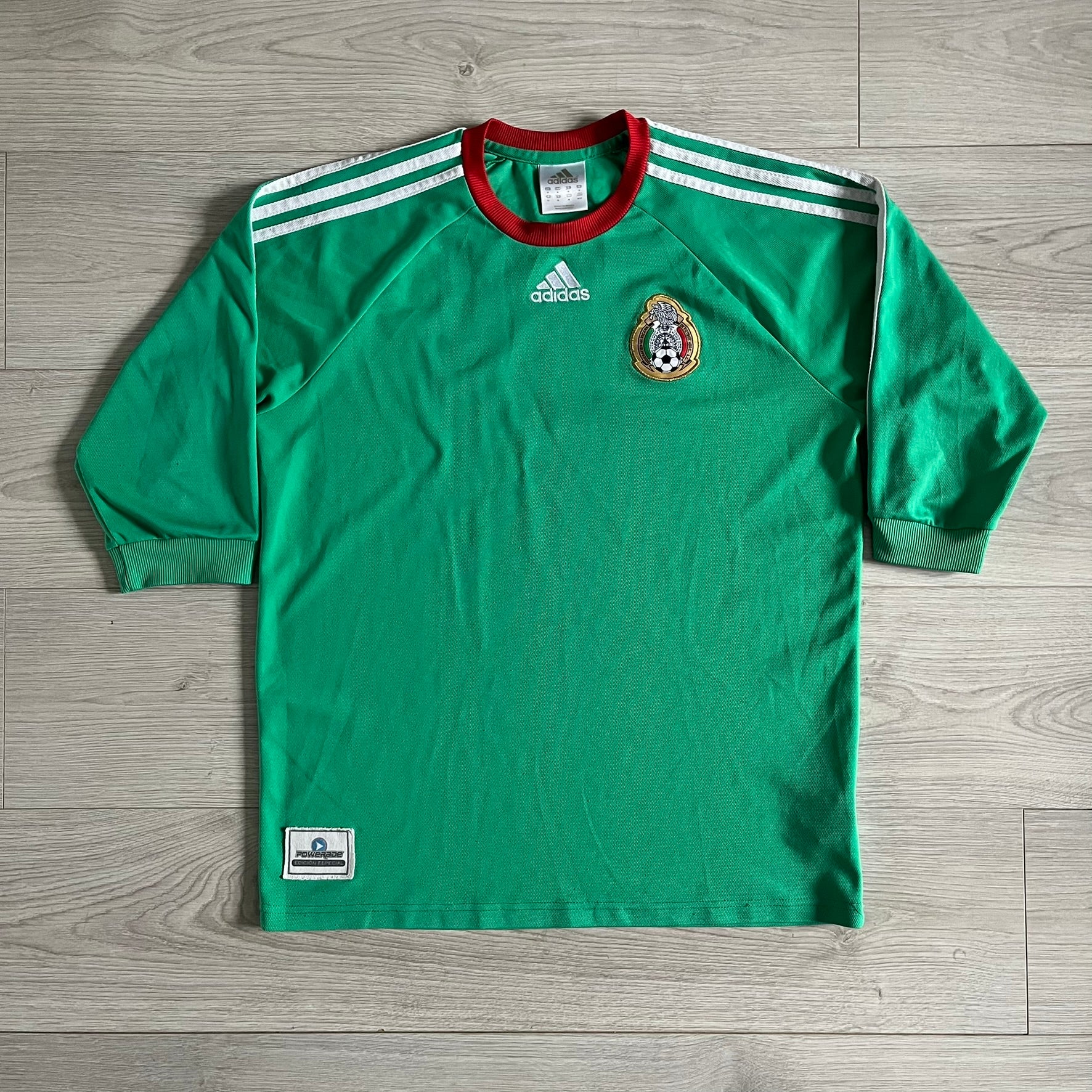 Adidas 2007-08 Mexico Powerade Limited Edition 3/4 Tee in green with red collar and white Adidas sleeve stripes. Features embroidered Adidas logo beneath the neck, Mexico crest on the heart, and a “Powerade Edición Especial” patch at the lower front. Extremely rare, issued only to select Coca-Cola store owners in Mexico.