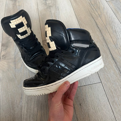 Adidas Originals 2013 M Attitude Logo Three Sneakers in black feature a leather and lacquer upper with a white rubber sole and blue interior lining. The tongue displays a large “3” made of small square details, and the heel has a trifold white adidas logo. Released in 2013, the Q23025 model highlights the M Attitude line design.