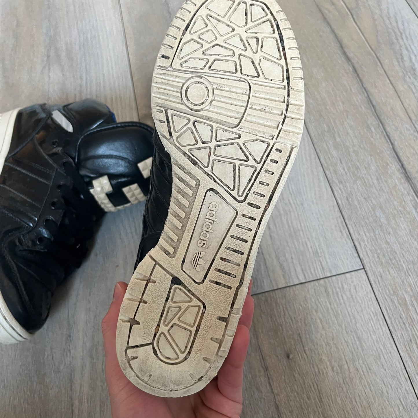 Adidas Originals 2013 M Attitude Logo Three Sneakers in black feature a leather and lacquer upper with a white rubber sole and blue interior lining. The tongue displays a large “3” made of small square details, and the heel has a trifold white adidas logo. Released in 2013, the Q23025 model highlights the M Attitude line design.