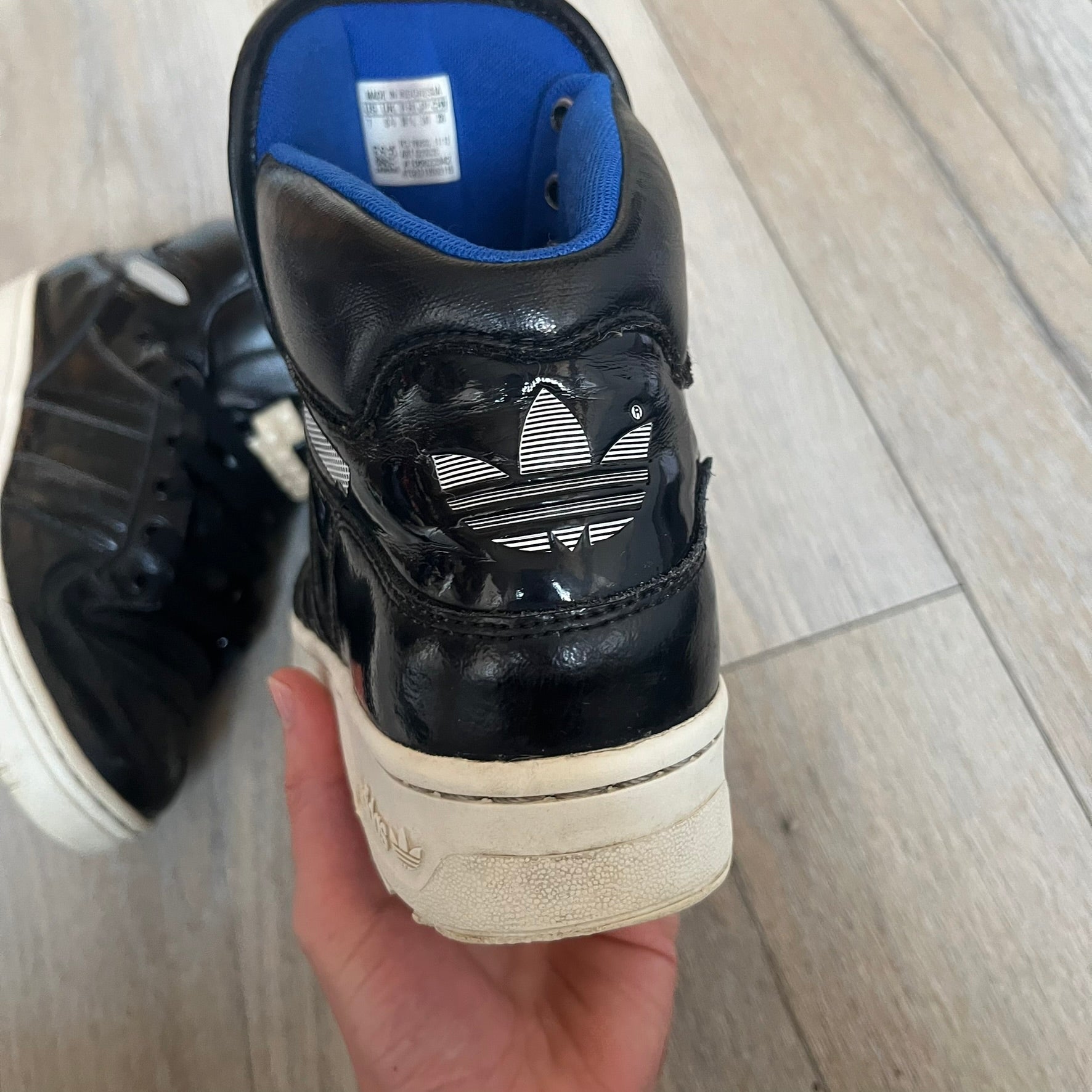 Adidas Originals 2013 M Attitude Logo Three Sneakers in black feature a leather and lacquer upper with a white rubber sole and blue interior lining. The tongue displays a large “3” made of small square details, and the heel has a trifold white adidas logo. Released in 2013, the Q23025 model highlights the M Attitude line design.