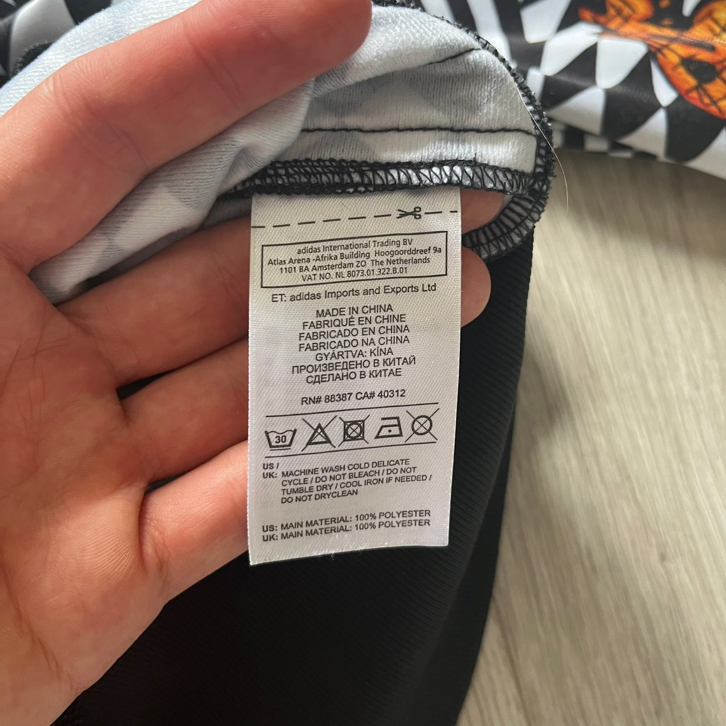 Hand holding a clothing tag with text on a blurred background