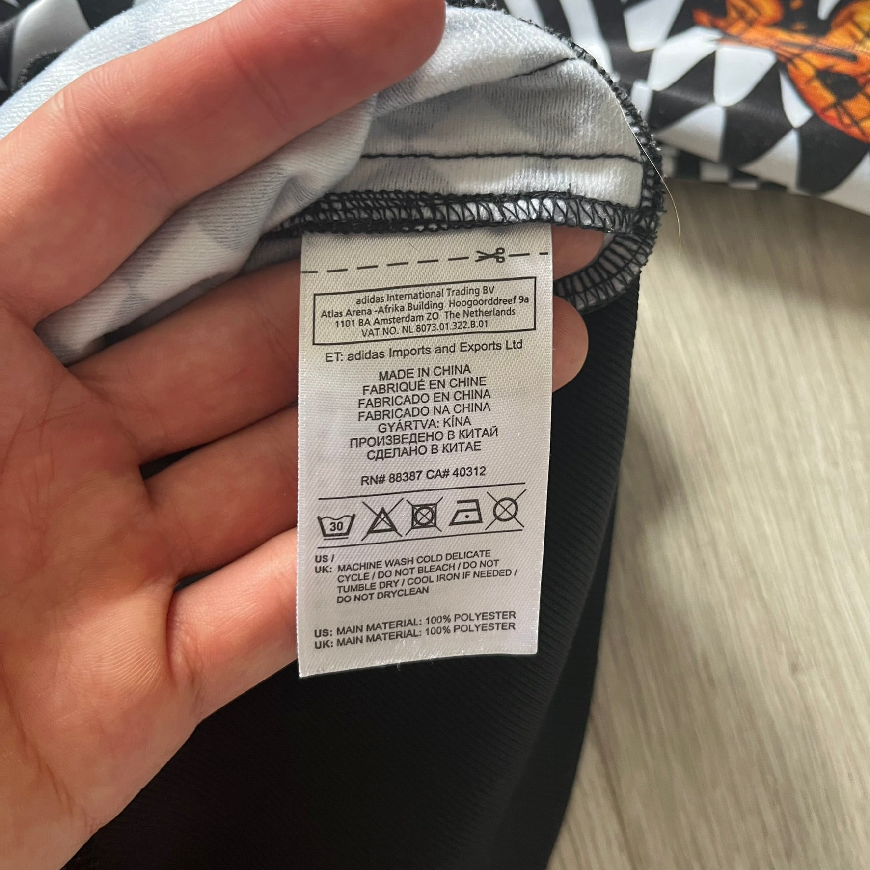 Hand holding a clothing tag with text on a blurred background