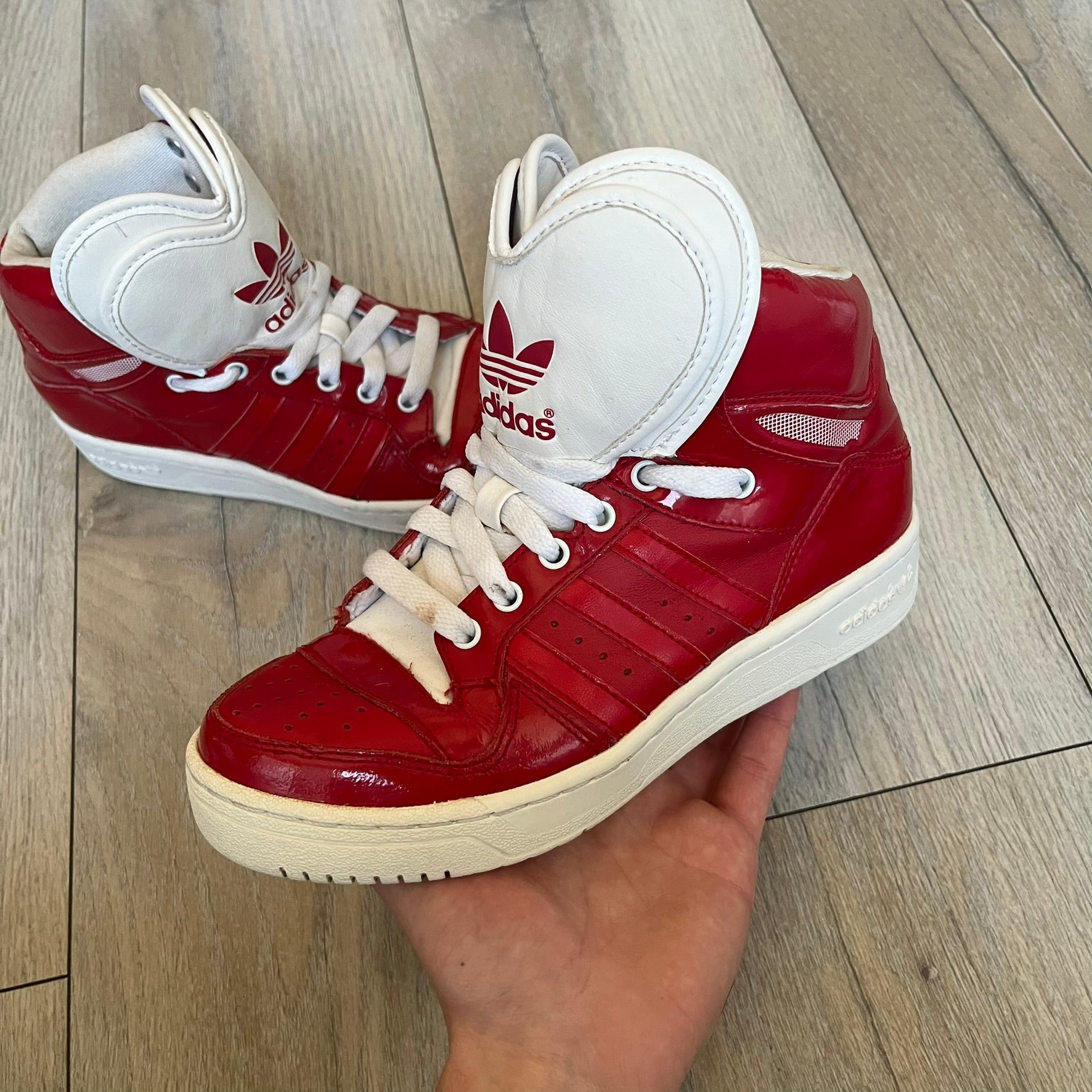 Adidas Originals Metro Attitude Logo Heart Sneakers are women’s sneakers released in 2012, featuring a red suede upper with matching University-Red accents. The design includes dual heart-shaped tongues in white with red Adidas logos, paired with a white sole and laces. Metro Attitude Logo Heart W model (G61014) inspired by Jeremy Scott collaborations.