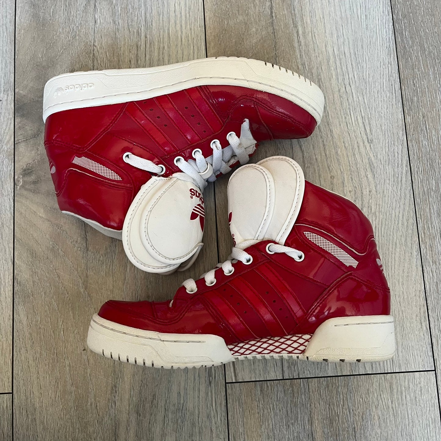 Adidas Originals Metro Attitude Logo Heart Sneakers are women’s sneakers released in 2012, featuring a red suede upper with matching University-Red accents. The design includes dual heart-shaped tongues in white with red Adidas logos, paired with a white sole and laces. Metro Attitude Logo Heart W model (G61014) inspired by Jeremy Scott collaborations.