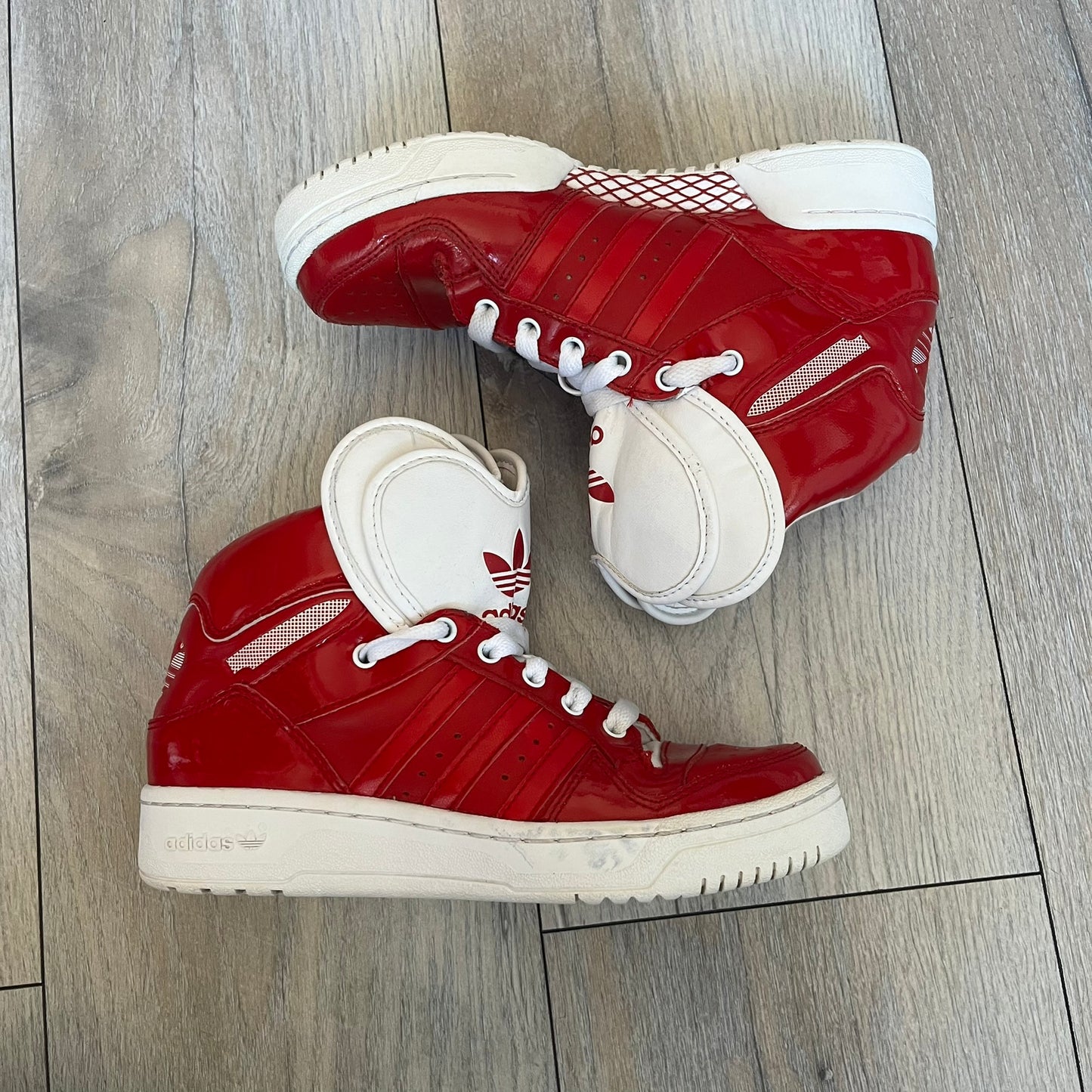 Adidas Originals Metro Attitude Logo Heart Sneakers are women’s sneakers released in 2012, featuring a red suede upper with matching University-Red accents. The design includes dual heart-shaped tongues in white with red Adidas logos, paired with a white sole and laces. Metro Attitude Logo Heart W model (G61014) inspired by Jeremy Scott collaborations.
