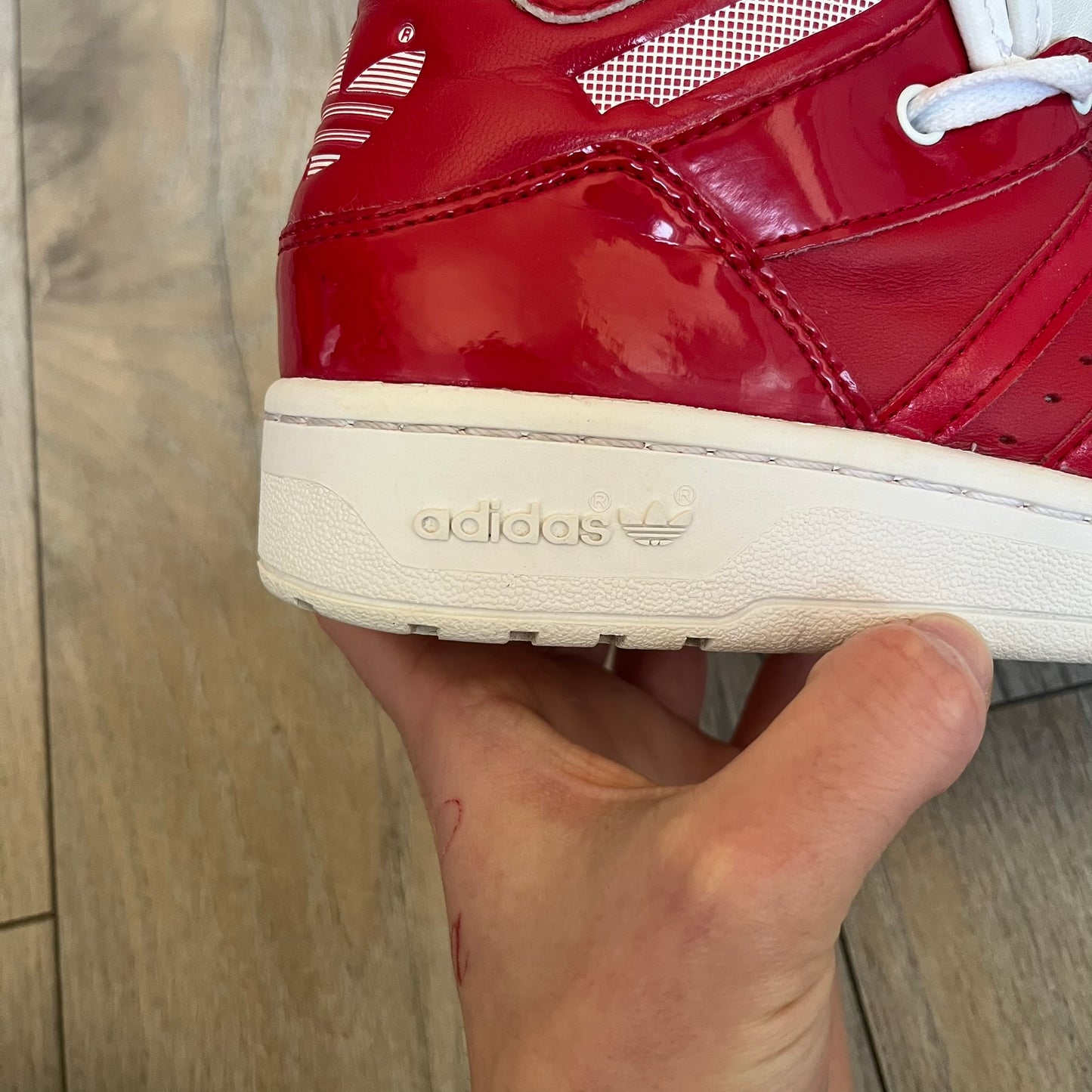 Adidas Originals Metro Attitude Logo Heart Sneakers are women’s sneakers released in 2012, featuring a red suede upper with matching University-Red accents. The design includes dual heart-shaped tongues in white with red Adidas logos, paired with a white sole and laces. Metro Attitude Logo Heart W model (G61014) inspired by Jeremy Scott collaborations.
