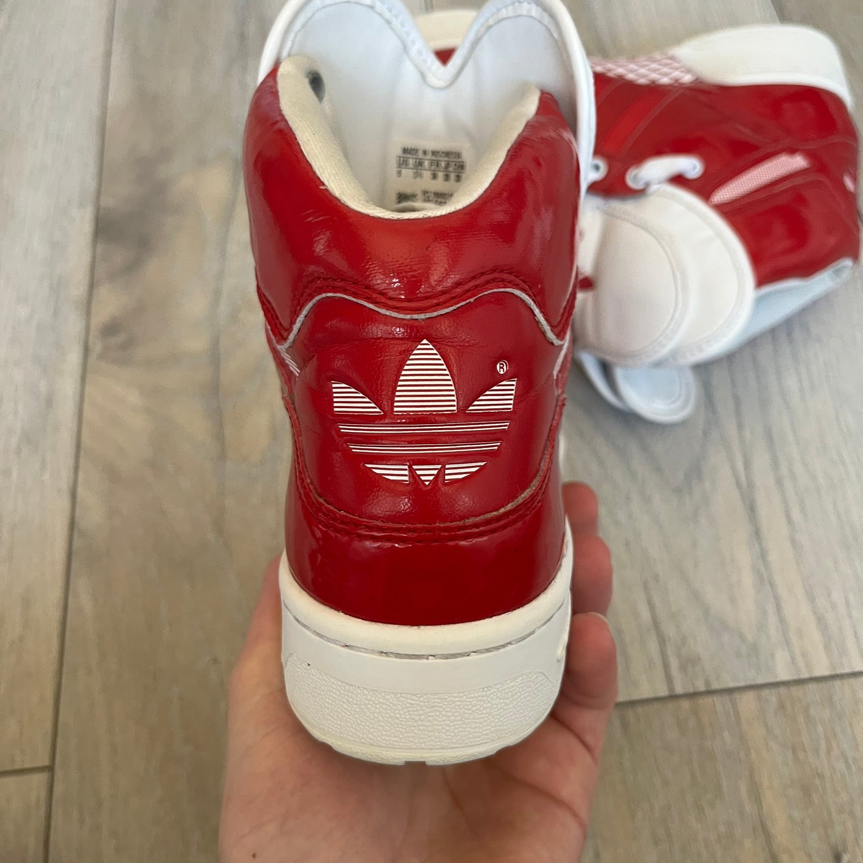 Adidas Originals Metro Attitude Logo Heart Sneakers are women’s sneakers released in 2012, featuring a red suede upper with matching University-Red accents. The design includes dual heart-shaped tongues in white with red Adidas logos, paired with a white sole and laces. Metro Attitude Logo Heart W model (G61014) inspired by Jeremy Scott collaborations.