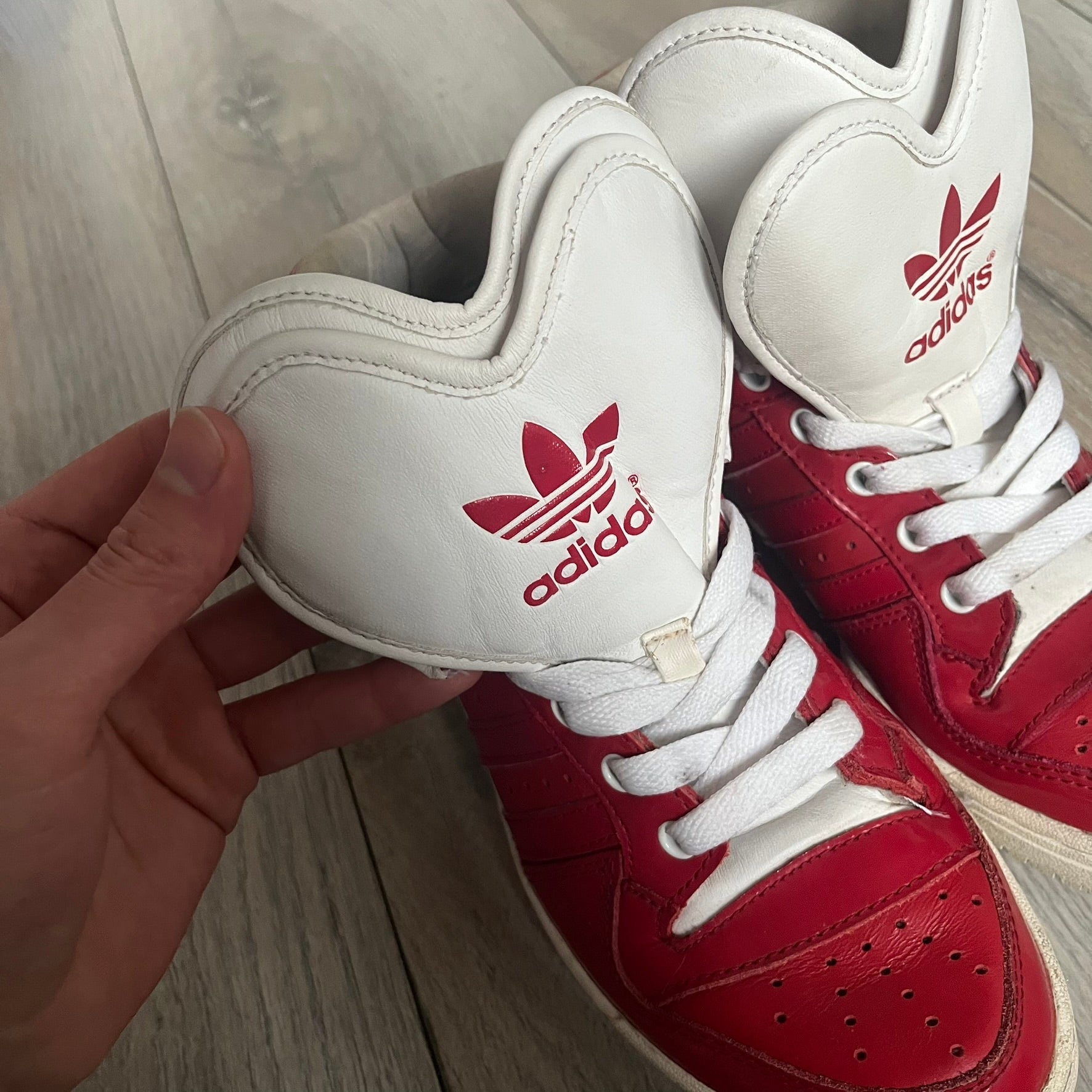 Adidas Originals Metro Attitude Logo Heart Sneakers are women’s sneakers released in 2012, featuring a red suede upper with matching University-Red accents. The design includes dual heart-shaped tongues in white with red Adidas logos, paired with a white sole and laces. Metro Attitude Logo Heart W model (G61014) inspired by Jeremy Scott collaborations.