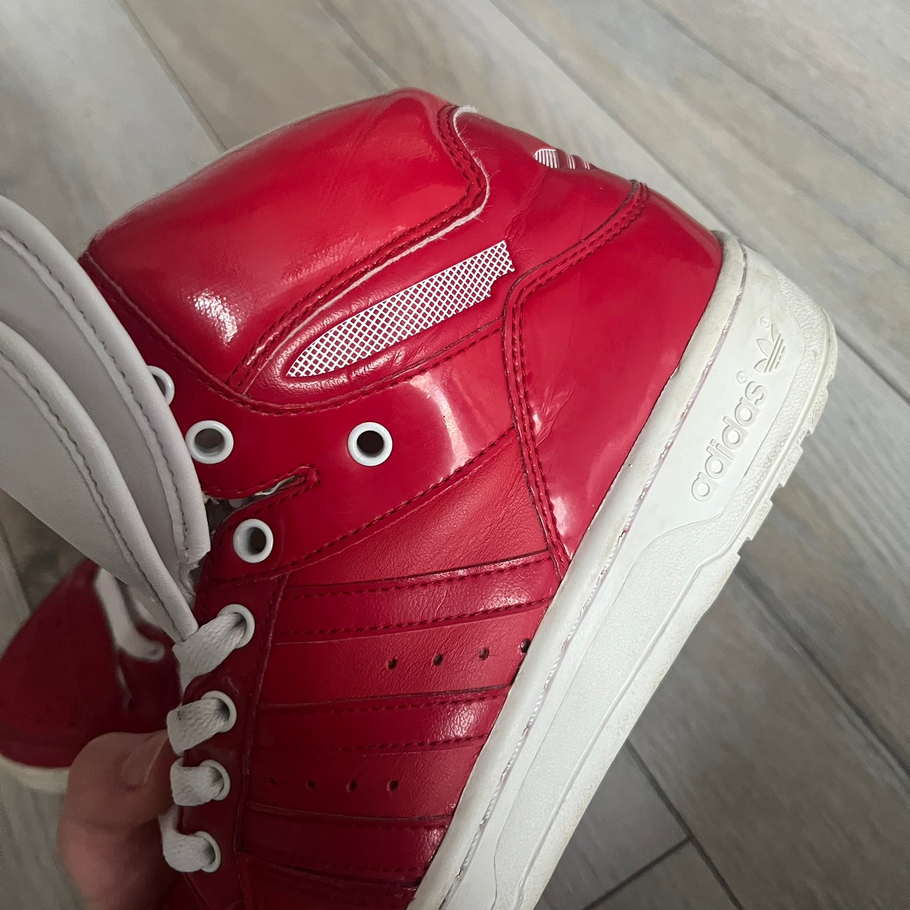 Adidas Originals Metro Attitude Logo Heart Sneakers are women’s sneakers released in 2012, featuring a red suede upper with matching University-Red accents. The design includes dual heart-shaped tongues in white with red Adidas logos, paired with a white sole and laces. Metro Attitude Logo Heart W model (G61014) inspired by Jeremy Scott collaborations.