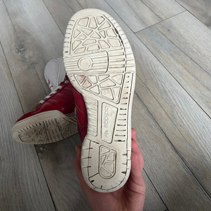 Adidas Originals Metro Attitude Logo Heart Sneakers are women’s sneakers released in 2012, featuring a red suede upper with matching University-Red accents. The design includes dual heart-shaped tongues in white with red Adidas logos, paired with a white sole and laces. Metro Attitude Logo Heart W model (G61014) inspired by Jeremy Scott collaborations.