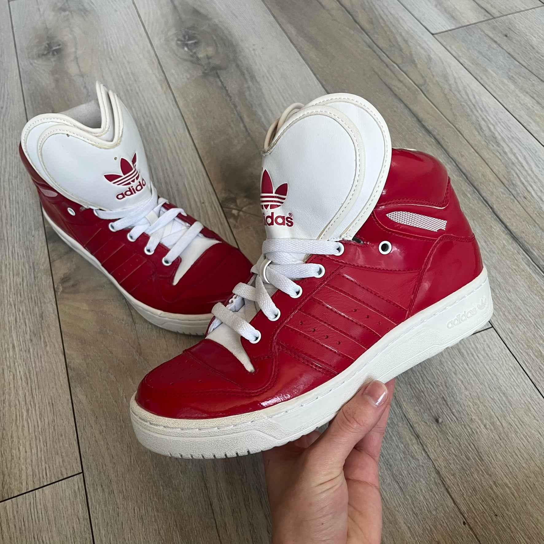 Adidas Originals Metro Attitude Logo Heart Sneakers are women’s sneakers released in 2012, featuring a red suede upper with matching University-Red accents. The design includes dual heart-shaped tongues in white with red Adidas logos, paired with a white sole and laces. Metro Attitude Logo Heart W model (G61014) inspired by Jeremy Scott collaborations