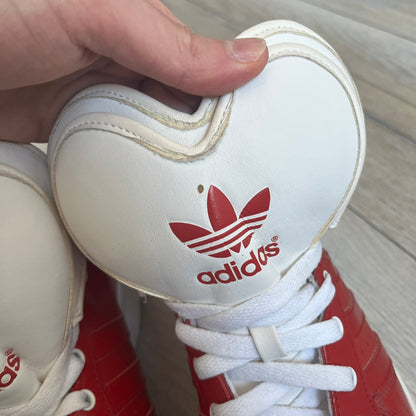 Adidas Originals Metro Attitude Logo Heart Sneakers are women’s sneakers released in 2012, featuring a red suede upper with matching University-Red accents. The design includes dual heart-shaped tongues in white with red Adidas logos, paired with a white sole and laces. Metro Attitude Logo Heart W model (G61014) inspired by Jeremy Scott collaborations