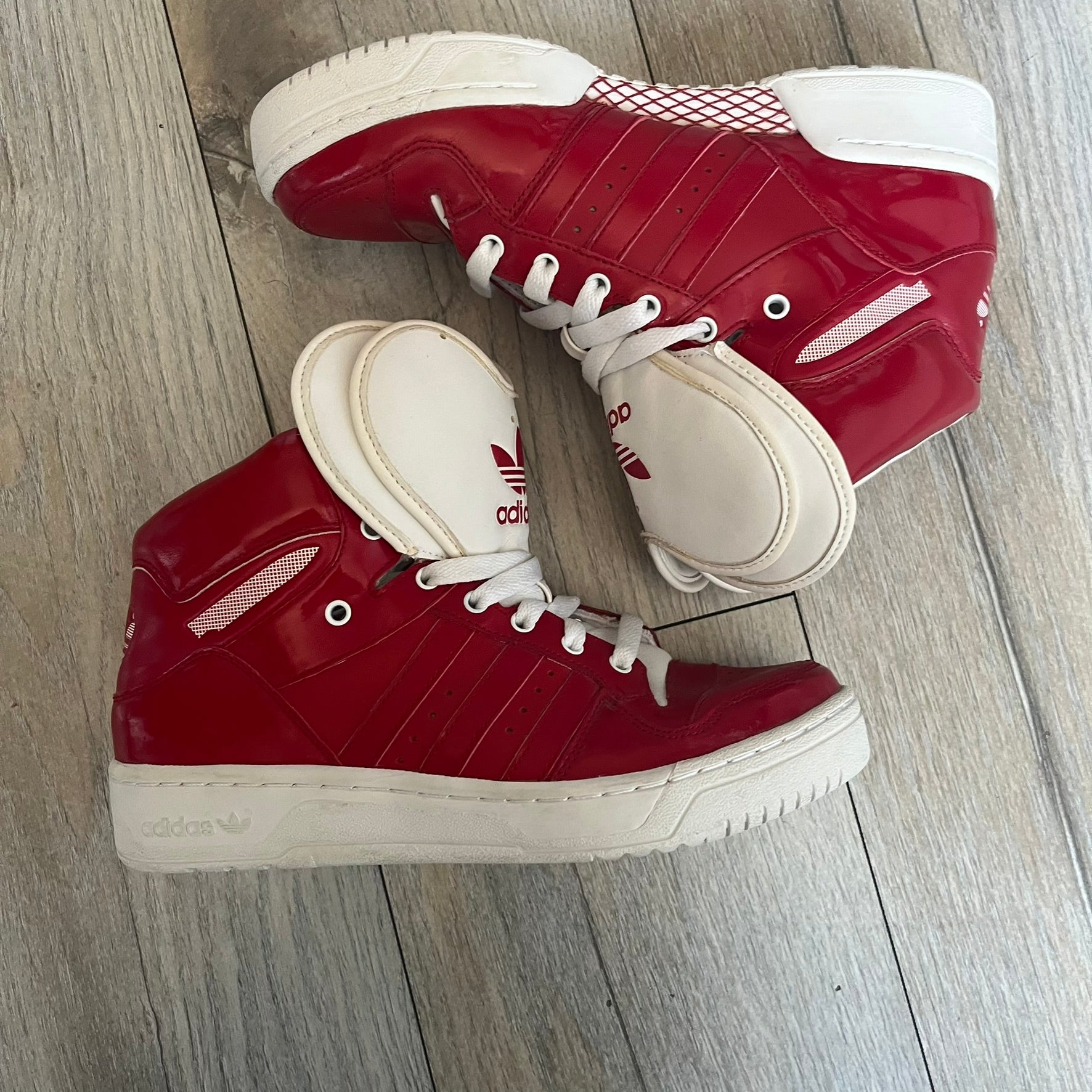 Adidas Originals Metro Attitude Logo Heart Sneakers are women’s sneakers released in 2012, featuring a red suede upper with matching University-Red accents. The design includes dual heart-shaped tongues in white with red Adidas logos, paired with a white sole and laces. Metro Attitude Logo Heart W model (G61014) inspired by Jeremy Scott collaborations