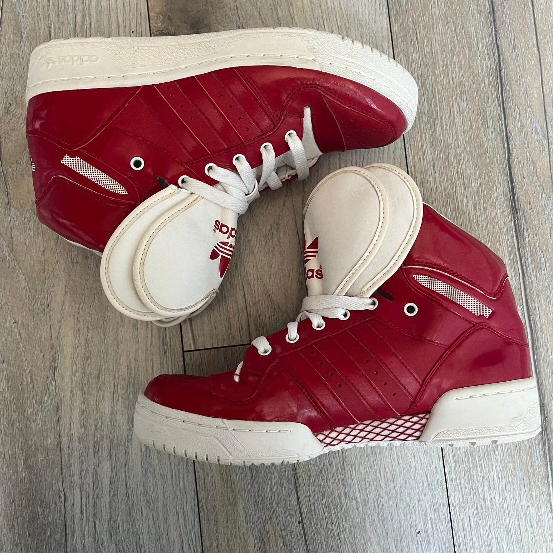 Adidas Originals Metro Attitude Logo Heart Sneakers are women’s sneakers released in 2012, featuring a red suede upper with matching University-Red accents. The design includes dual heart-shaped tongues in white with red Adidas logos, paired with a white sole and laces. Metro Attitude Logo Heart W model (G61014) inspired by Jeremy Scott collaborations