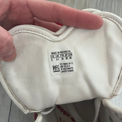 Adidas Originals Metro Attitude Logo Heart Sneakers are women’s sneakers released in 2012, featuring a red suede upper with matching University-Red accents. The design includes dual heart-shaped tongues in white with red Adidas logos, paired with a white sole and laces. Metro Attitude Logo Heart W model (G61014) inspired by Jeremy Scott collaborations.