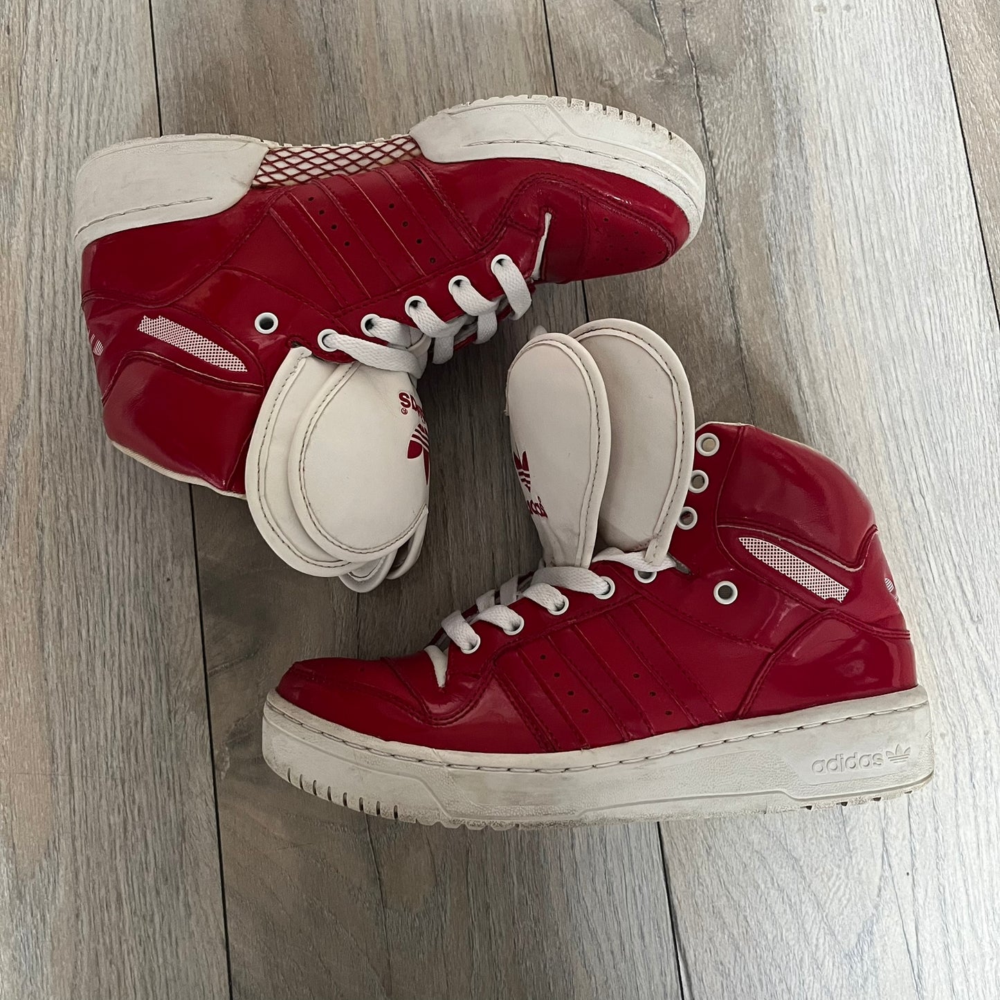 Adidas Originals Metro Attitude Logo Heart Sneakers are women’s sneakers released in 2012, featuring a red suede upper with matching University-Red accents. The design includes dual heart-shaped tongues in white with red Adidas logos, paired with a white sole and laces. Metro Attitude Logo Heart W model (G61014) inspired by Jeremy Scott collaborations.