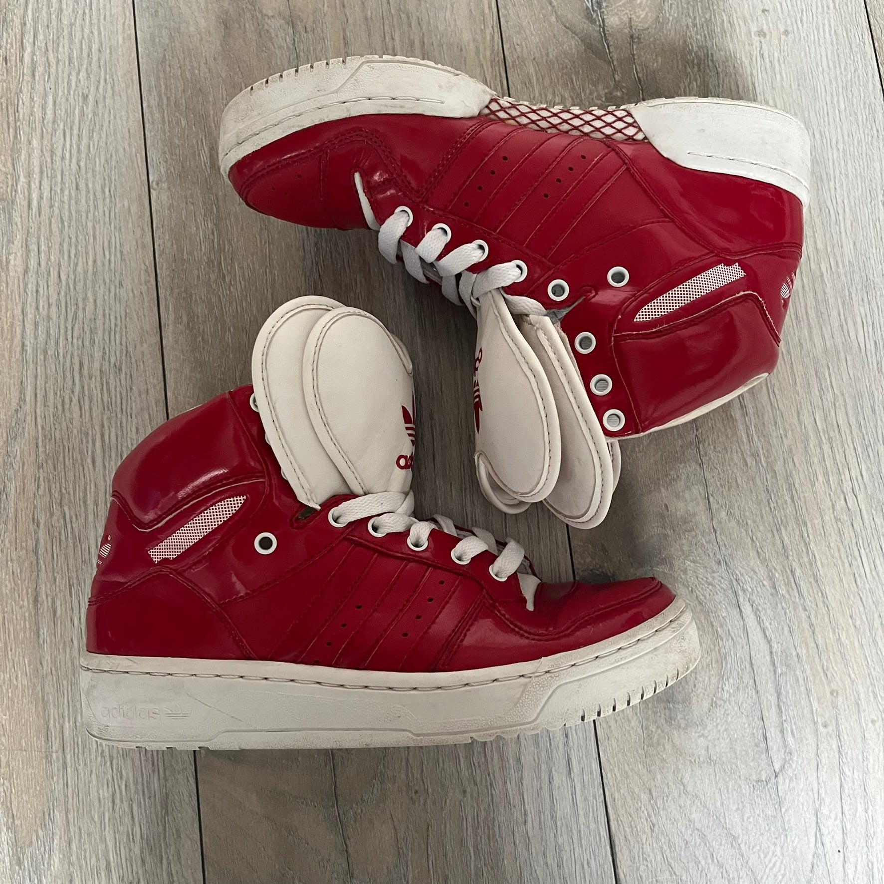 Adidas Originals Metro Attitude Logo Heart Sneakers are women’s sneakers released in 2012, featuring a red suede upper with matching University-Red accents. The design includes dual heart-shaped tongues in white with red Adidas logos, paired with a white sole and laces. Metro Attitude Logo Heart W model (G61014) inspired by Jeremy Scott collaborations.